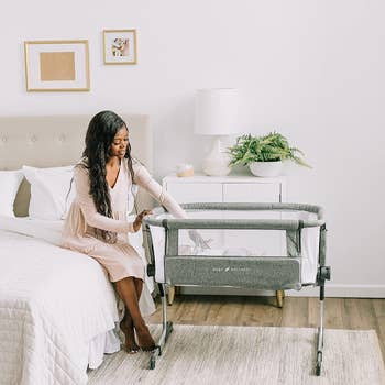 parent sitting up in bed beside bassinet 