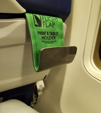 reviewer photo of the tablet holder attached to a seat back tray on an airplane