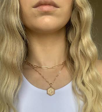 reviewer wearing the gold necklace set in the letter A with a white top