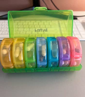 reviewer photo of the green pill organizer holding colorful compartments