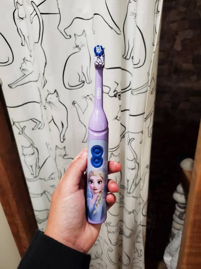 reviewer holding a purple toothbrush with elsa on it