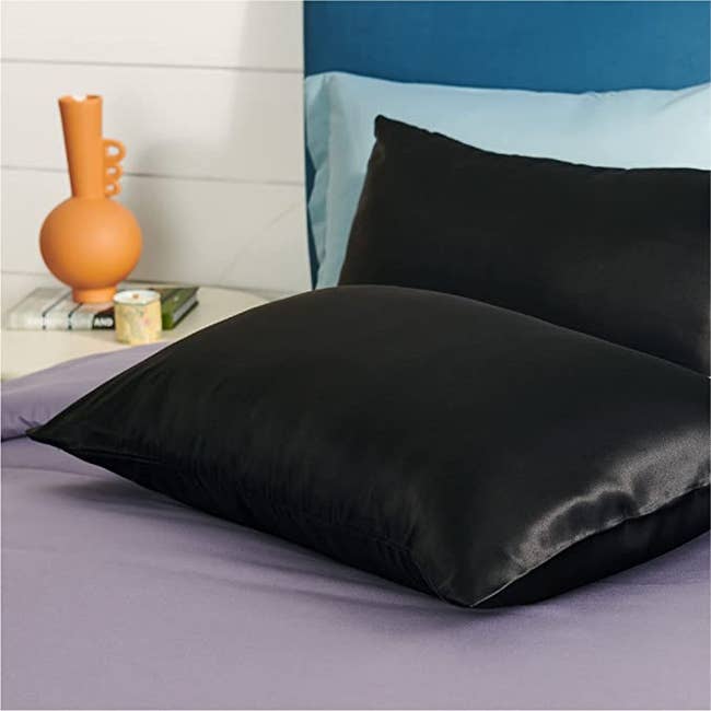 Two black satin pillows on a bed
