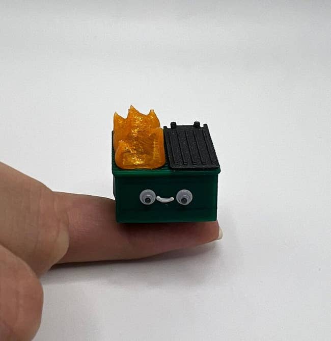 a mini 3d-printed smiling dumpster that's on fire