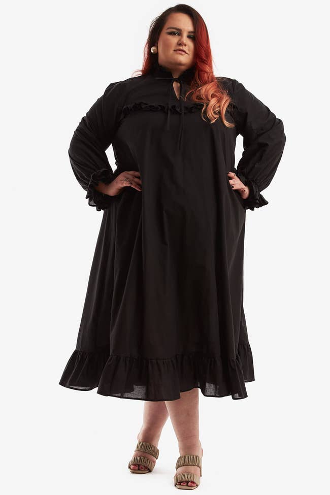 a model wearing a long sleeve black night gown with ruffle details 