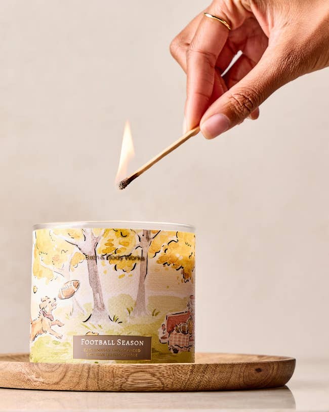 Hand lighting a candle labeled