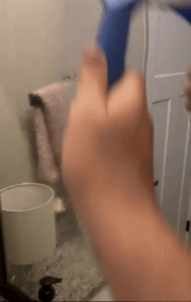 Person successful  a bath  utilizing a bluish  towel to screen  a country   camera for privacy