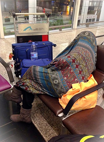 a person wrapped up in the blanket at an airport 