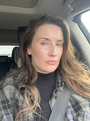 Person sitting successful  a car, wearing a plaid garment  implicit    a achromatic  top, with agelong  hairsbreadth  styled naturally