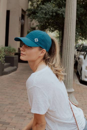Model in a blue baseball cap with a high ponytail coming out of the back  
