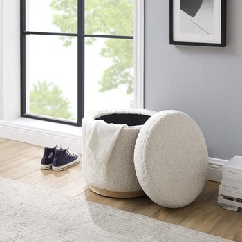 the white boucle ottoman with a blanket inside