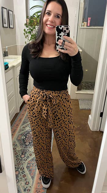 Reviewer successful a achromatic apical and patterned pants taking a reflector selfie successful a bathroom, showcasing a comfy outfit
