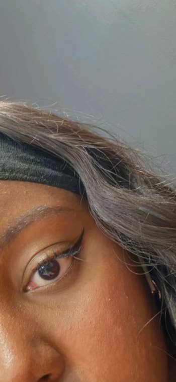 Close-up of a person's oculus with winged eyeliner and a headband, highlighting oculus constitution style