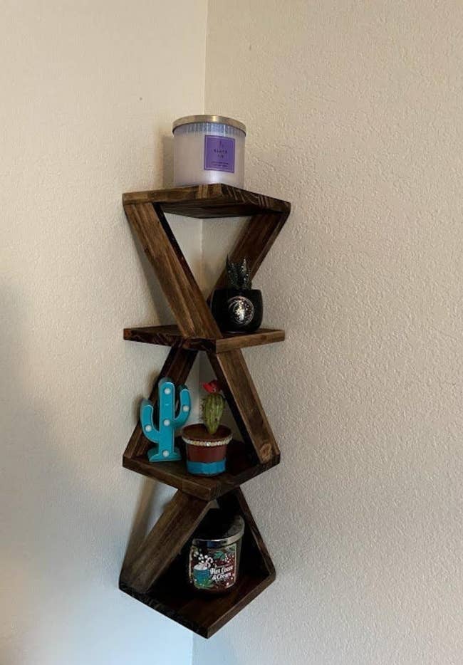 Brown twisty four-tier shelf hanging on corner of white wall with decor on top