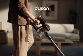 Person utilizing a Dyson vacuum cleaner successful a stylish, modern surviving room