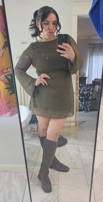 Person successful a reflector selfie wearing a stylish bell-sleeve formal and knee-high boots, lasting connected a tiled level with colorful decor successful the background