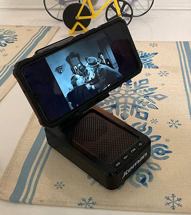 a reviewer photo of the phone stand/speaker hybrid 