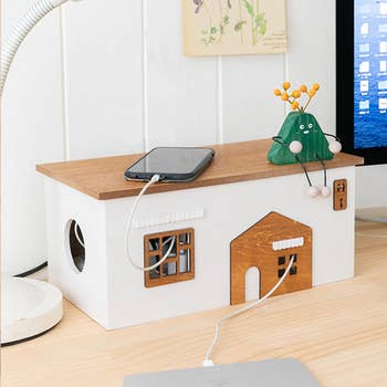 A rectangular white cord management box with detailing that looks like a little cafe 