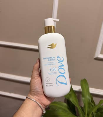 Hand holding a Dove Hydration Boost Body Wash with a pump dispenser, suitable for moisturizing tegument care
