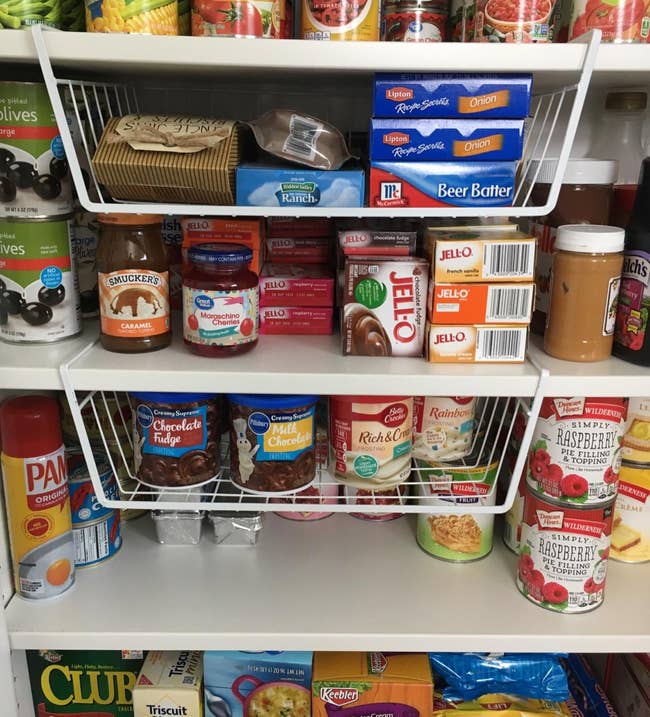 reviewer's white under-shelf baskets in the pantry holding various items