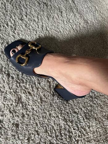 A ft wearing an elegant heeled mule with golden embellishments