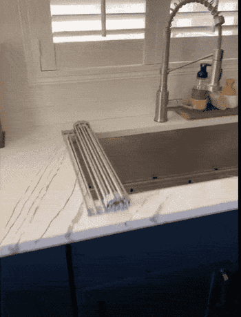 Gif of reviewer rolling the rack over the corner of their sink