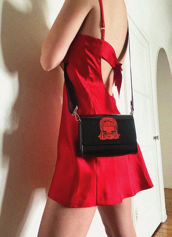 model wearing black crossbody bag with red Lucy design