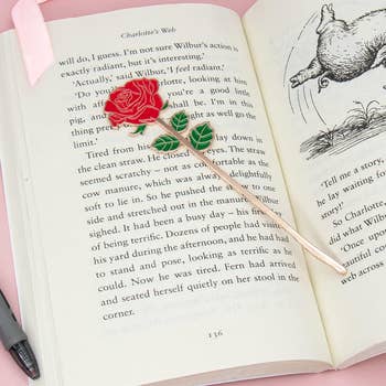 A gold stemmed red rose metal bookmark on a page 