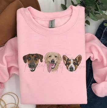 a pink sweatshirt with three dog faces on it