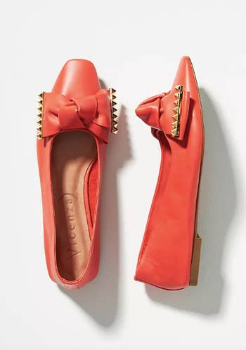 coral flats with knotted bow that has gold studs on the edges
