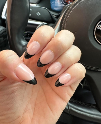 Person's hand displaying long press on nails with a black and clear French manicure