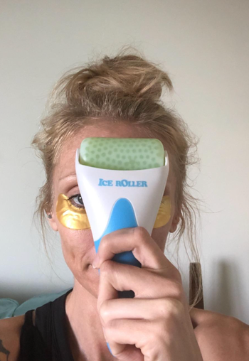 Reviewer holding green facial roller to their face 