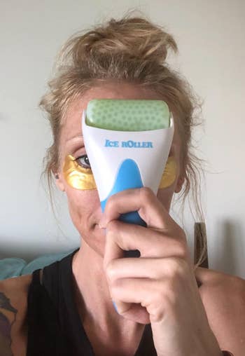 Reviewer holding green facial roller to their face 