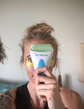 Reviewer holding green facial roller to their face 