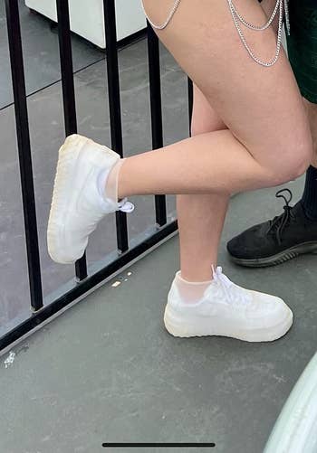 reviewer wearing white shoes with a white cover over them