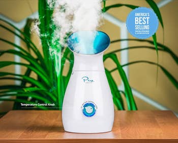 Facial steamer releasing steam, labeled arsenic America's best-selling model. Shows somesthesia power knob connected a wood array with greenish works backdrop