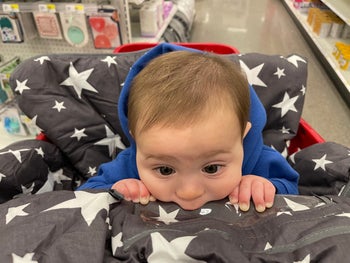 a baby sitting in a grey shopping cart cover with white stars