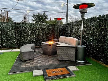 Outdoor patio acceptable   with grey  wicker seats astir   a occurrence  pit connected  a tiled surface, flanked by gangly  patio heaters, surrounded by gangly  hedges