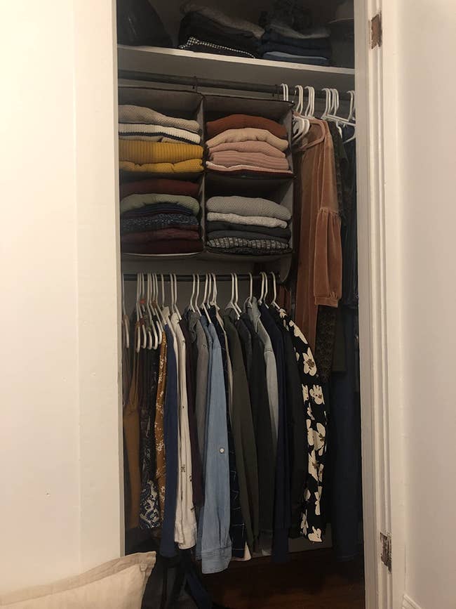 reviewer's closet with the hanging organizer packed with clothes and folded clothes