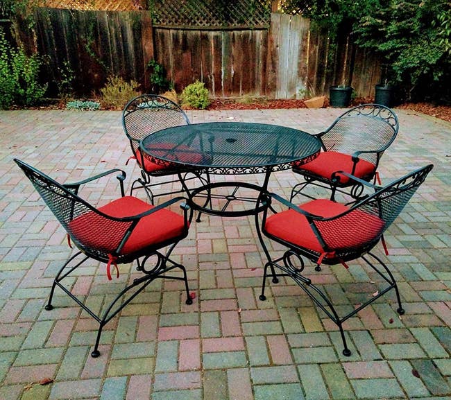 Reviewer image of round wrought iron chairs and red cushions around a circular table outside