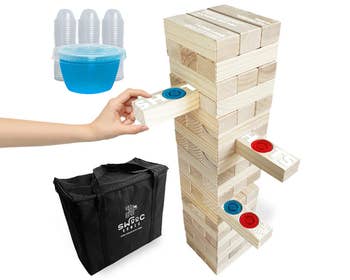 a hand pulling out a Jenga block with a blue jello shot in it