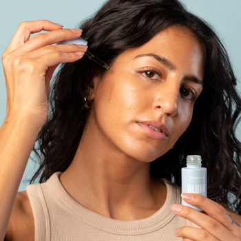 model applies the Meltdown Acne Oil to an area on their face