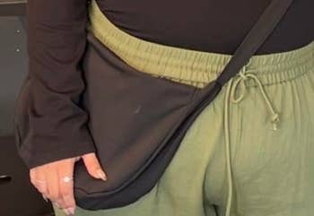 Person wearing a black long-sleeve top, green drawstring pants, and a black crossbody bag