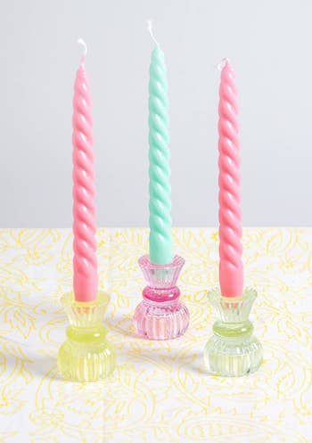 three candles in the mini size candlestick holders in yellow, pink, and light green