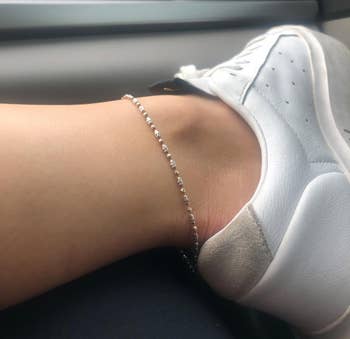Reviewer wearing the chain ankle bracelet with white shoes