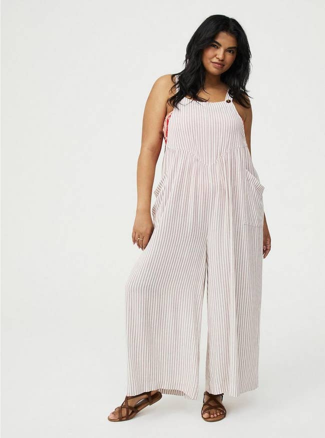 Person wearing striped overalls and sandals, posing successful  a relaxed mode  for a manner  shoot