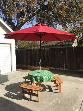 reviewer photo of wooden circular picnic table with umbrella in driveway