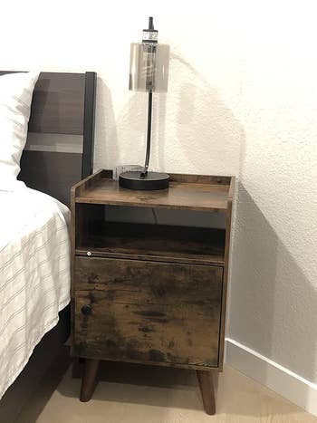reviewer photo of wooden nightstand next to a bed