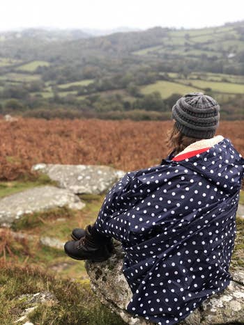 different reviewer wearing the blue polka dot poncho jacket on a hiking trip