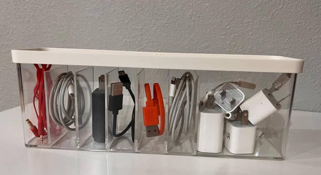 a reviewer photo of the cord organizer bin with various charging cords inside 