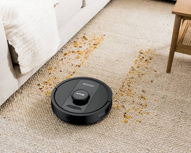 Robot vacuum cleaning a carpet with scattered debris, showcasing powerful suction and efficient performance on various floor types